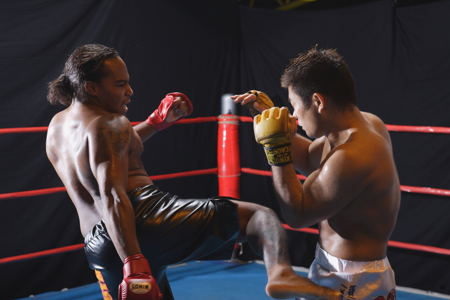 MMA fighters exchanging kicks and punches inside a competition ring.