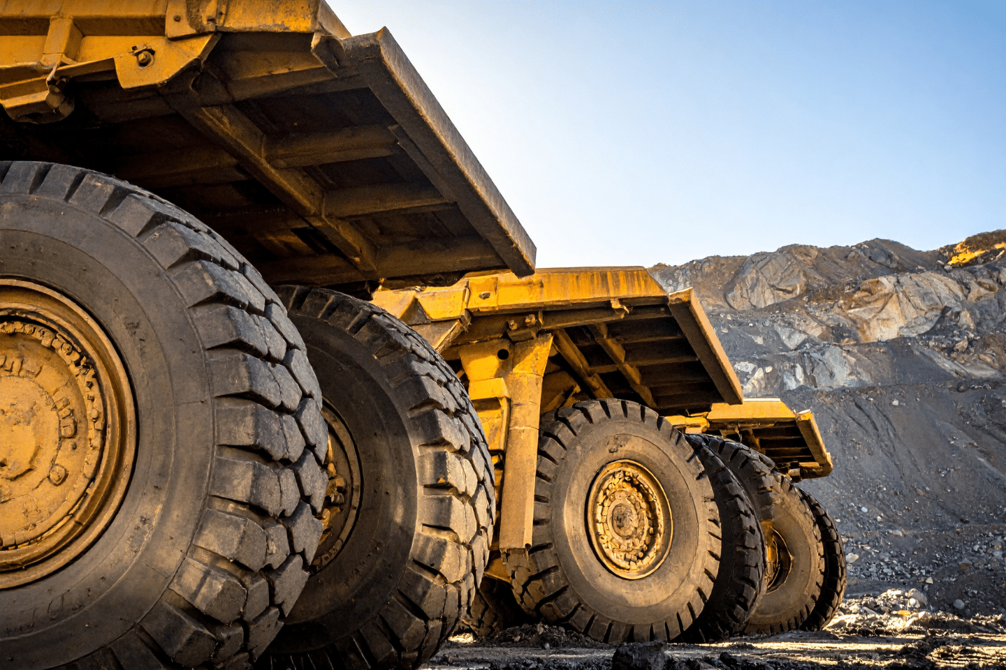 Massive dump trucks with oversized tires lined up at a mining or construction site.