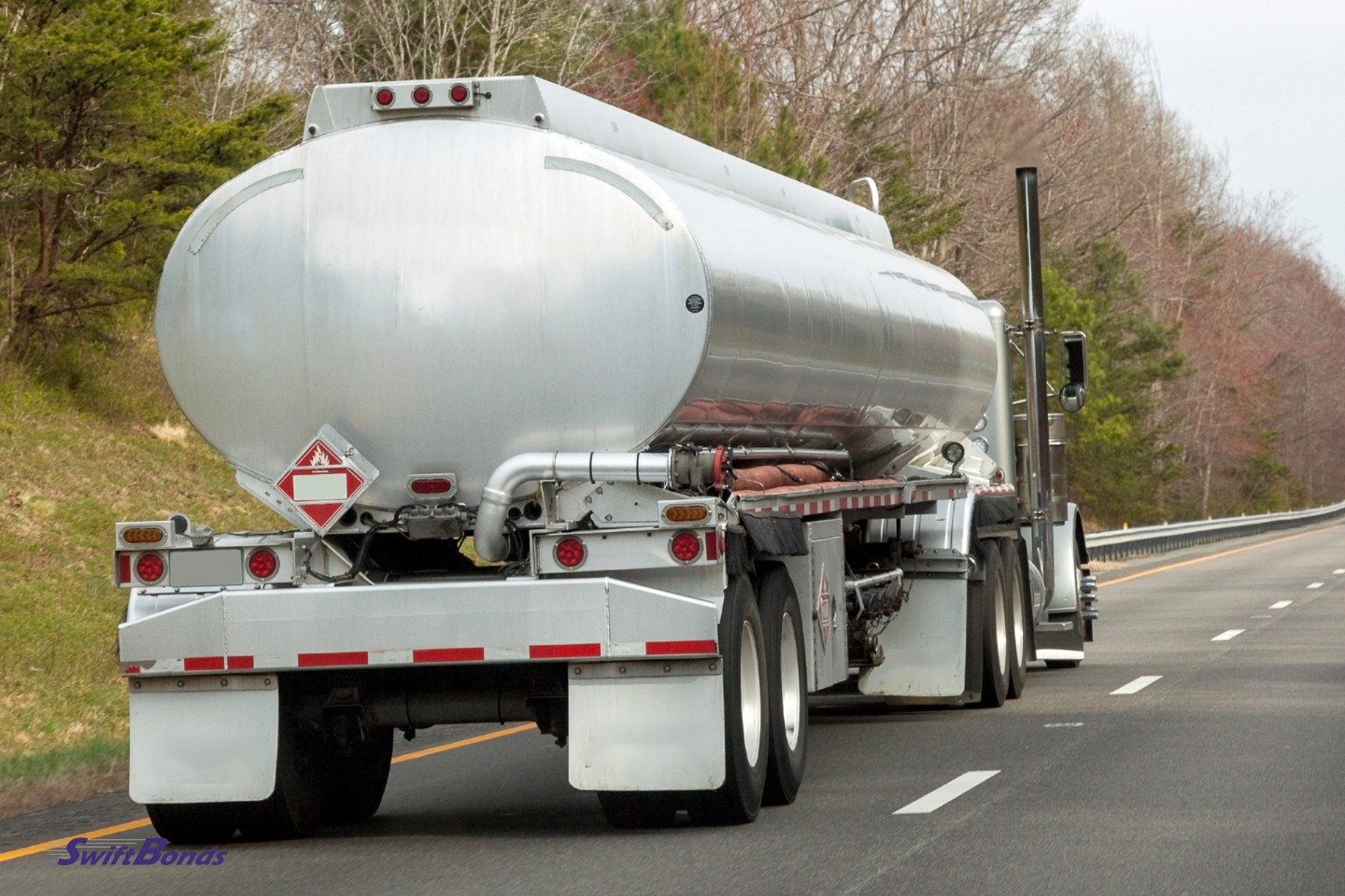 A highway fuel truck with trees in the backdrop.