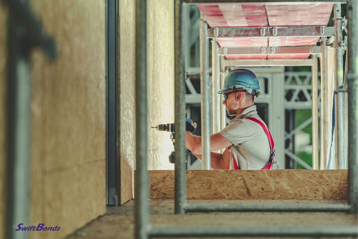 A contractor works on a wall with a drill.