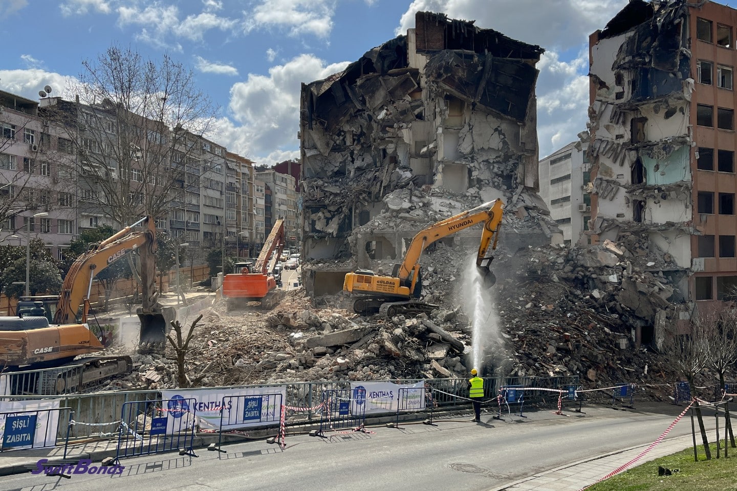 An orange bulldozer and contractors are seen beside a demolished structure in the downtown area.
