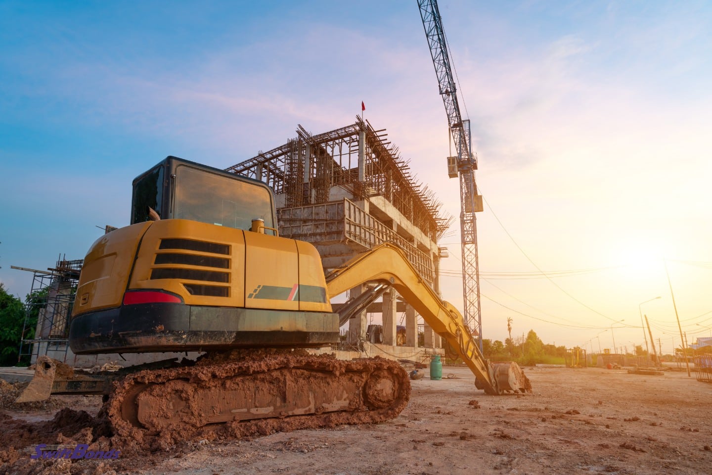Excavator on construction site with sunset background.