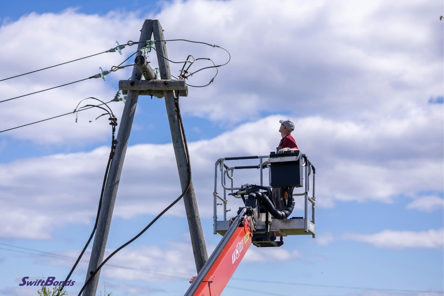 A utility worker is fixing electricity cables on an elevator.