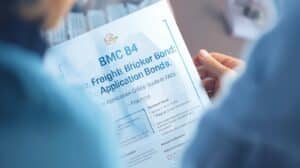 Close-up of a person holding a printed BMC 84 Freight Broker Bond guide and FAQs with highlighted details.