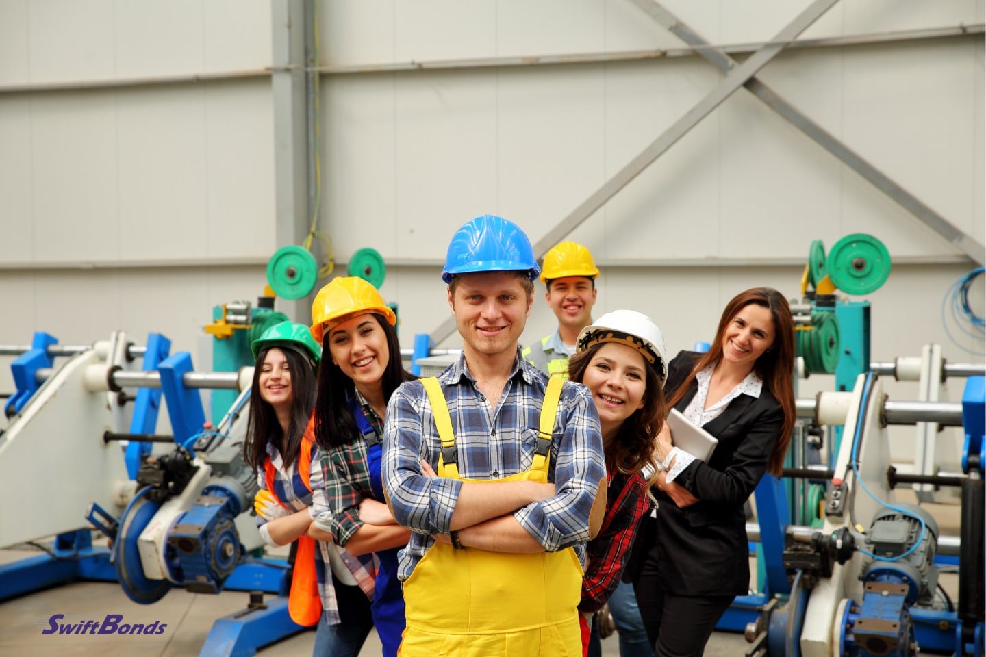Factory workers wearing uniforms and hard helmets.