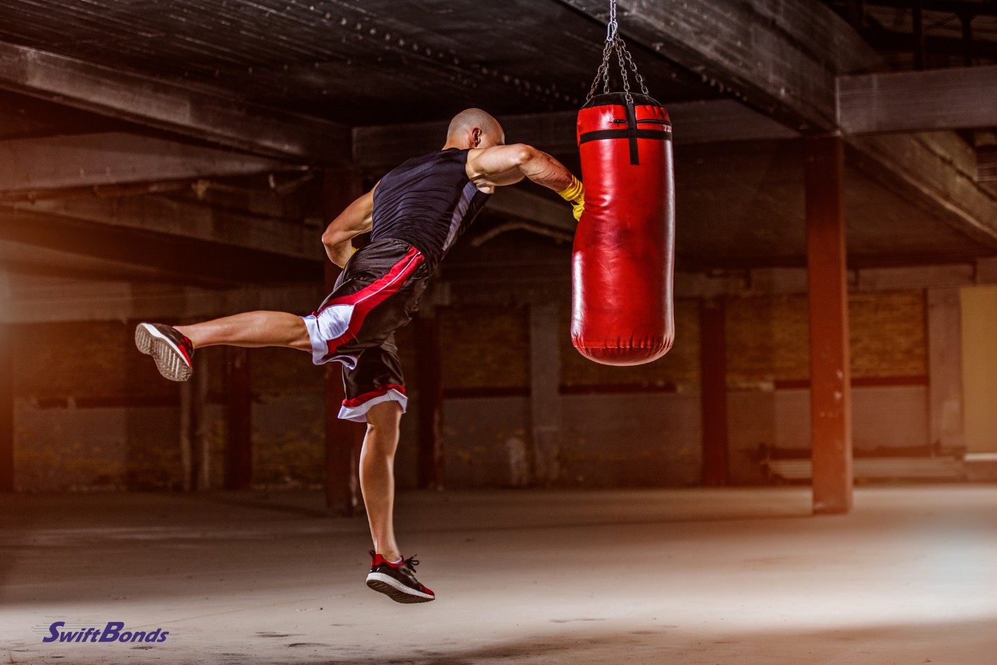 Athletic men use a punching bag to hone their boxing techniques.