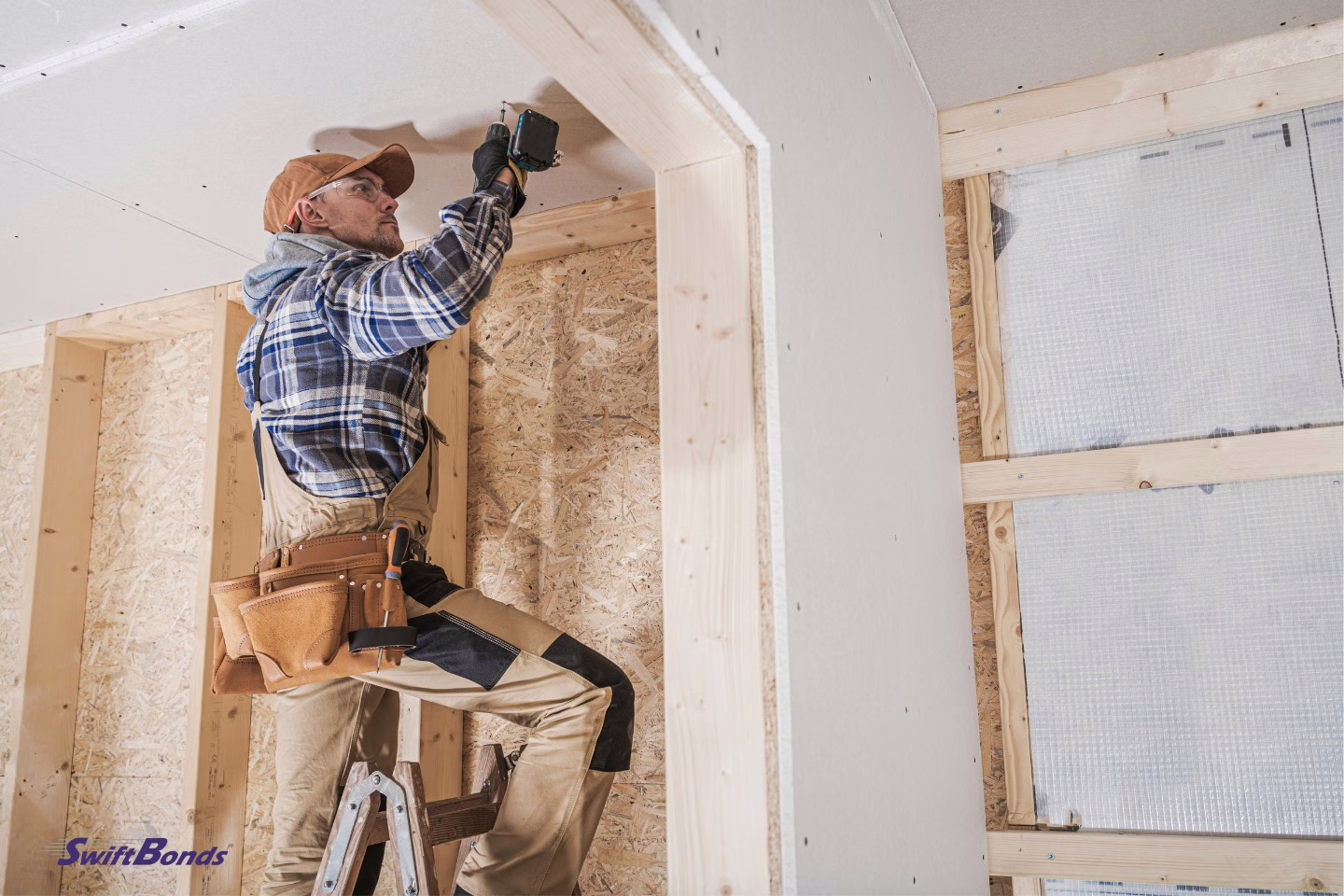 A general contractor uses a cordless drill driver to apply drywall.