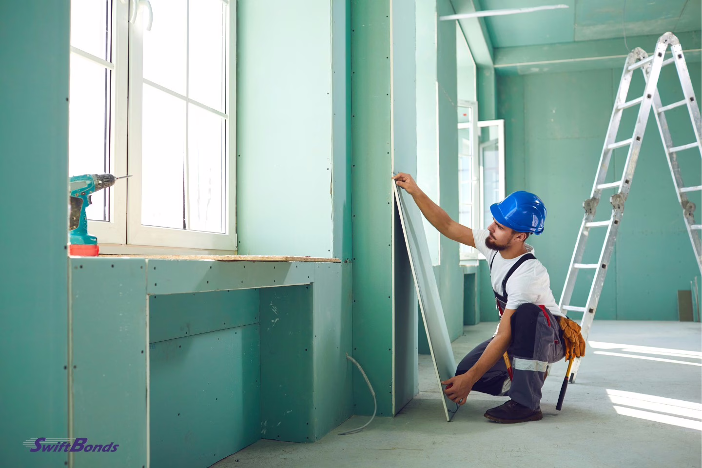 A construction worker installs green plasterboard drywall.