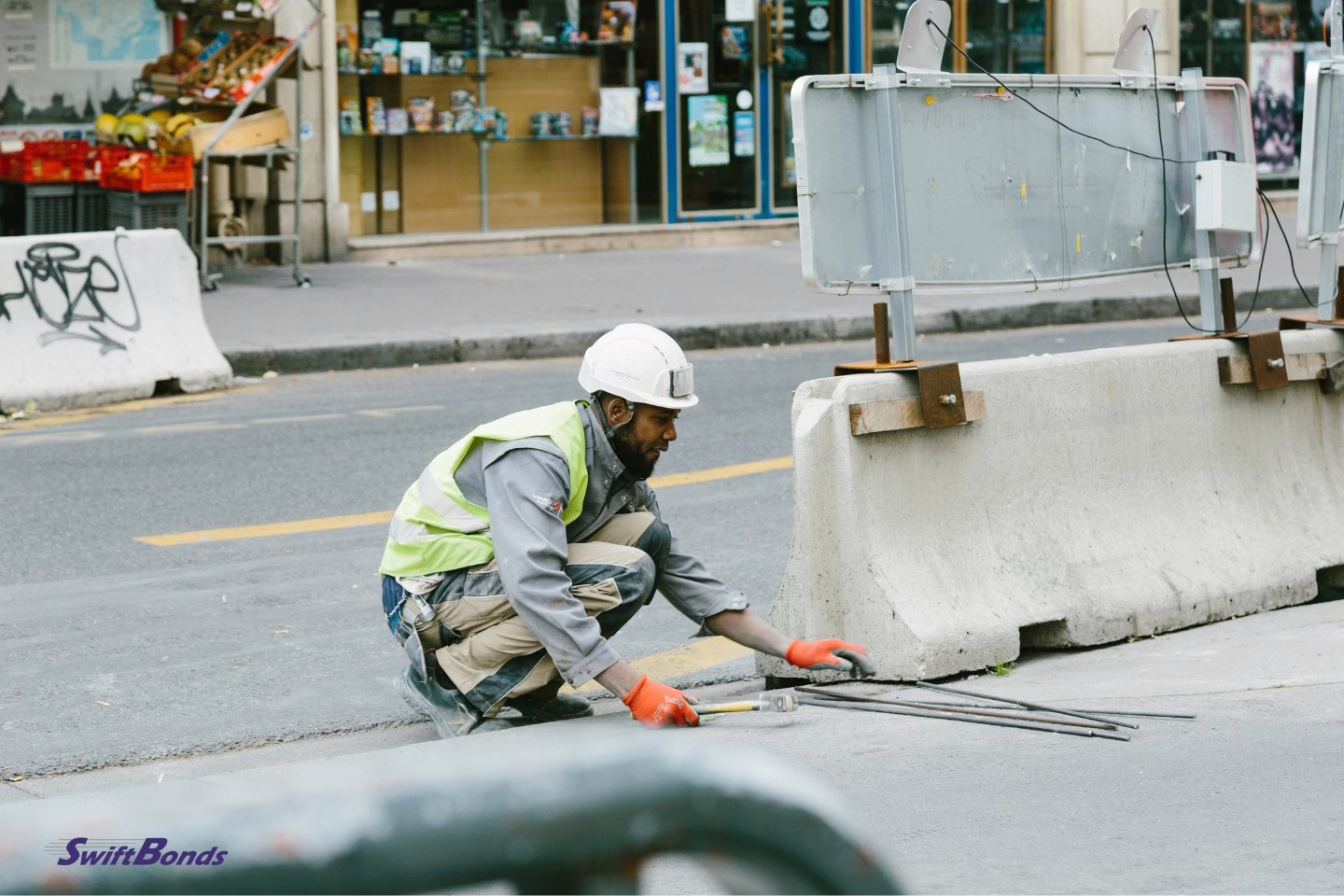 A man with a white hard hat is working on a road.
