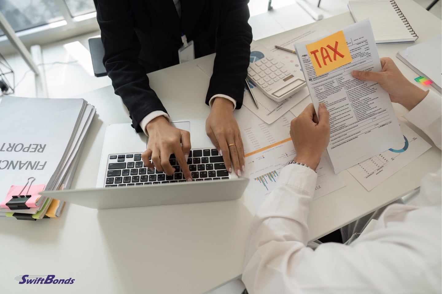 At the office desk, a tax adviser helps a client with tax paperwork and financial reports.