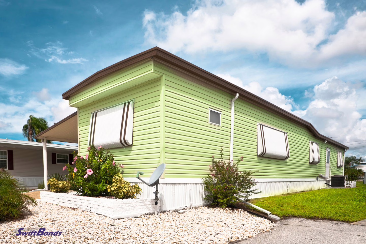 A green manufactured house with a satellite dish.