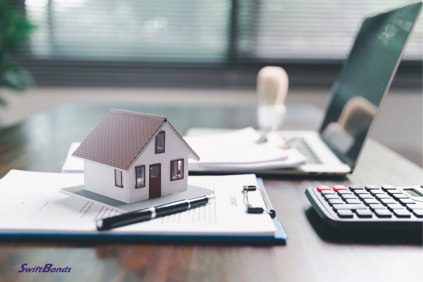 A house model next to paperwork on a table represents investing in real estate.