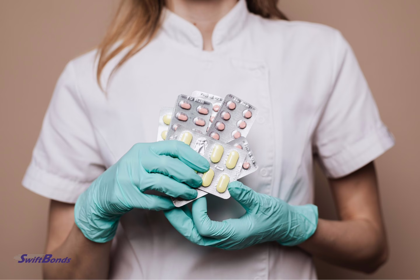 Pharmacist holding a selection of medicines, preparing or organizing prescriptions in a pharmacy setting.