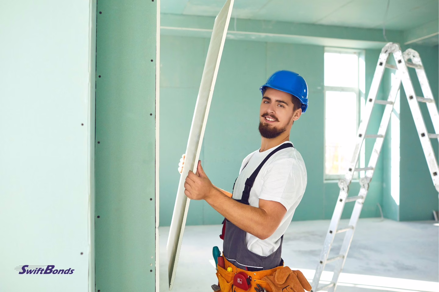 Construction worker installing plasterboard drywall inside a building under construction.